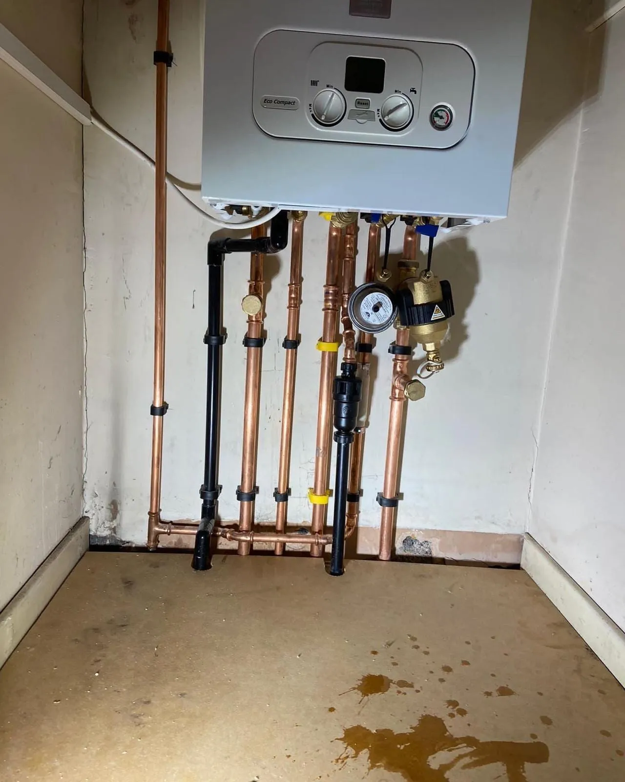 A boiler with the copper pipework, isolation valves and system filter dressed in below it