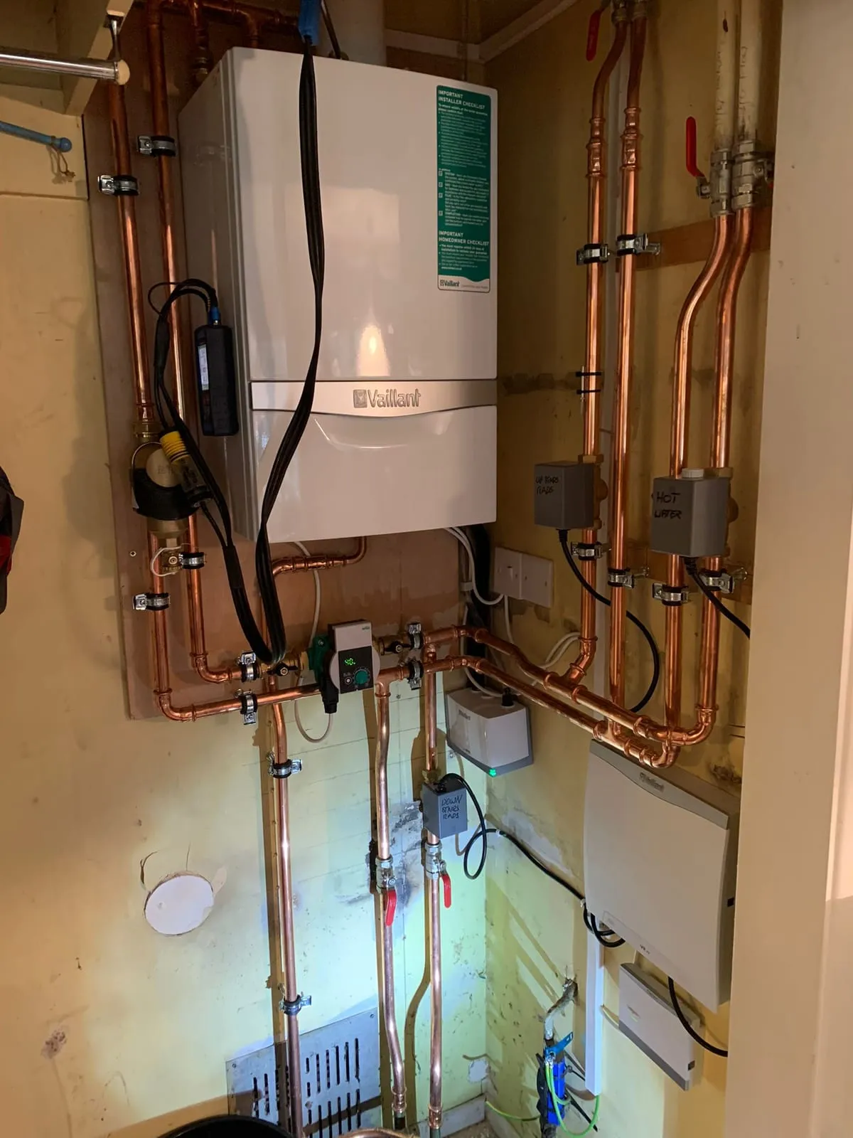 A newly installed gas boiler with fresh copper pipework and isolation valves beneath it