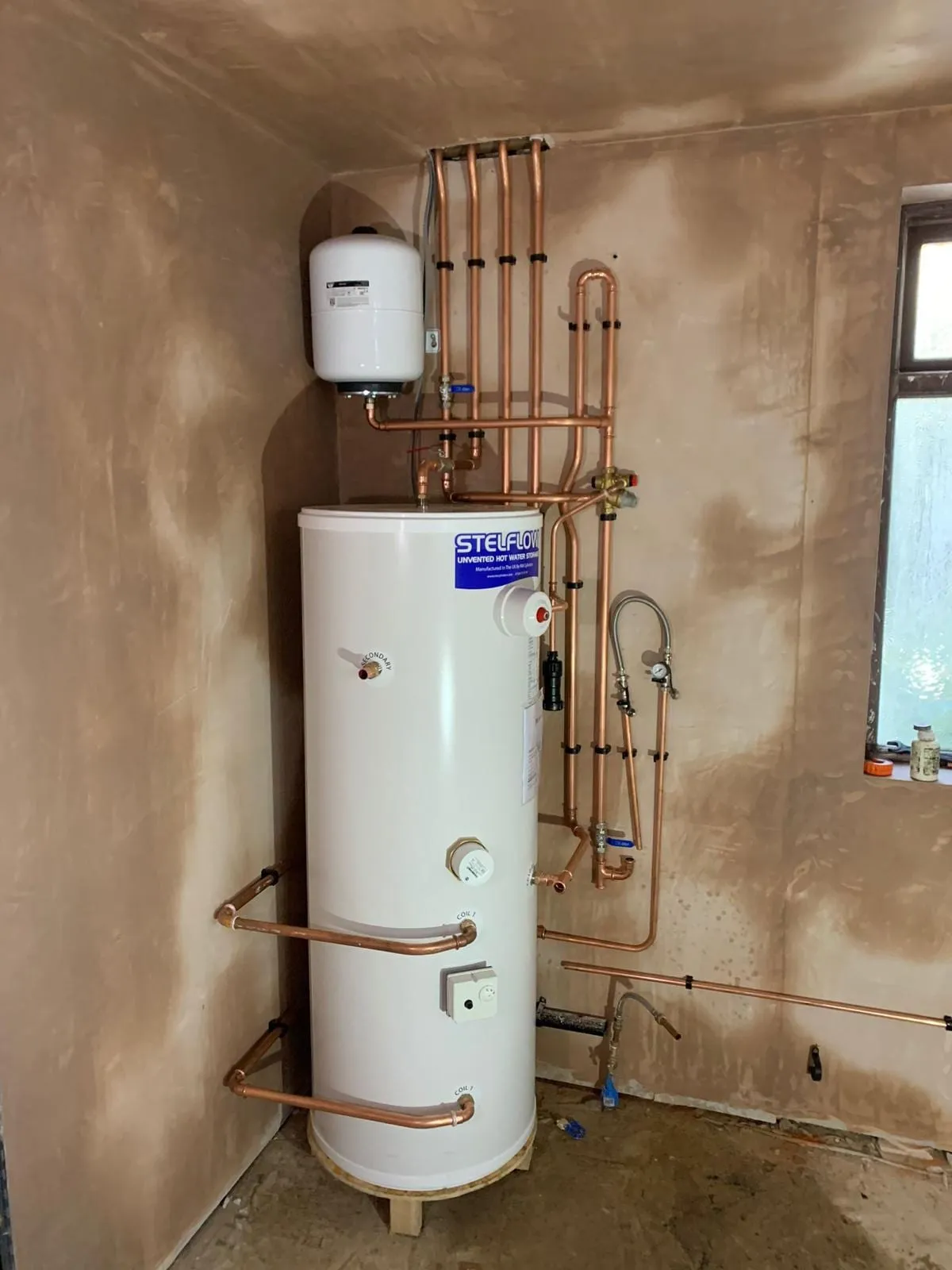 An unvented hot water cylinder with its copper pipework and safety valves